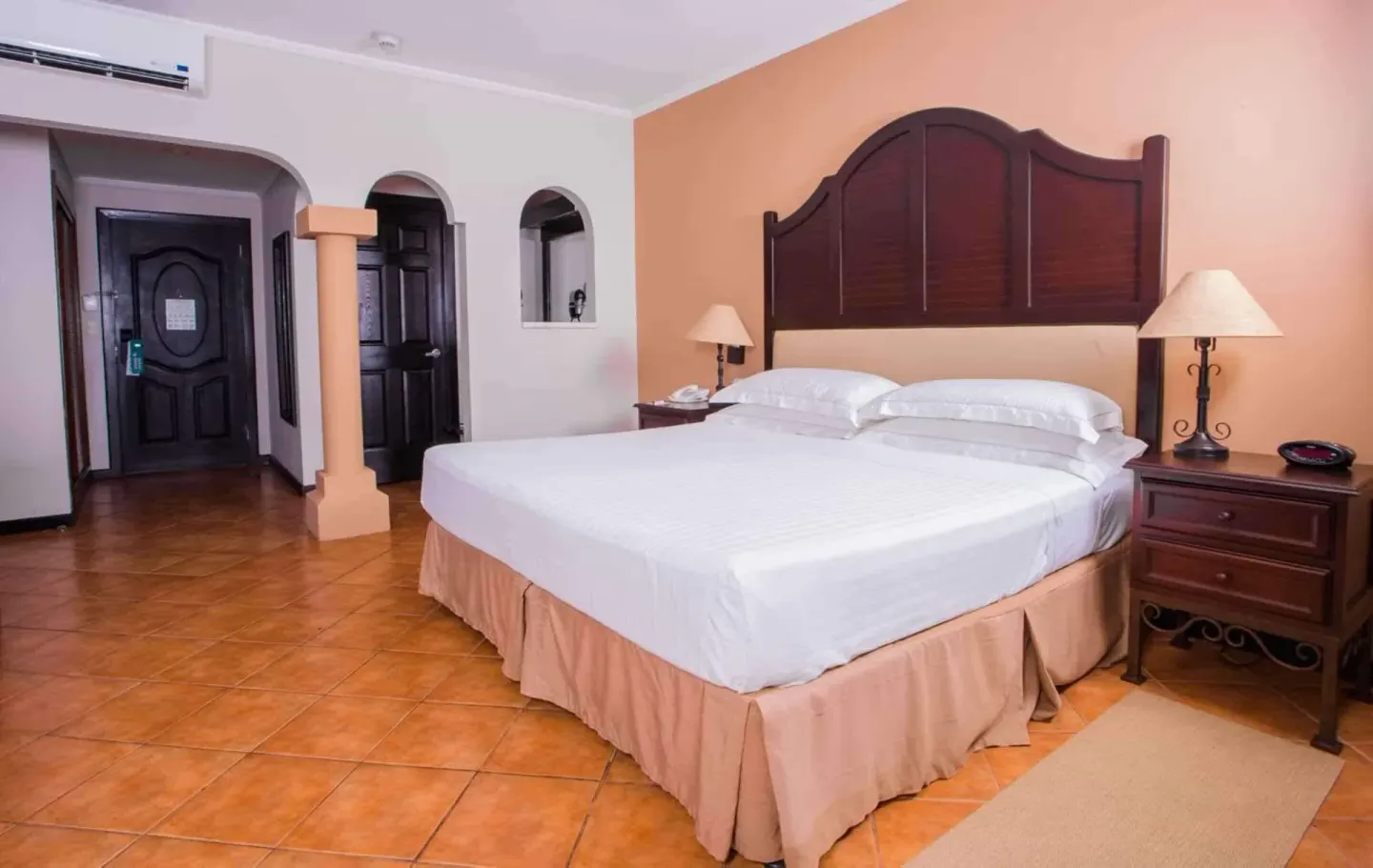 Deluxe Room king bed with arched entry and bedside tables at Occidental Papagayo.