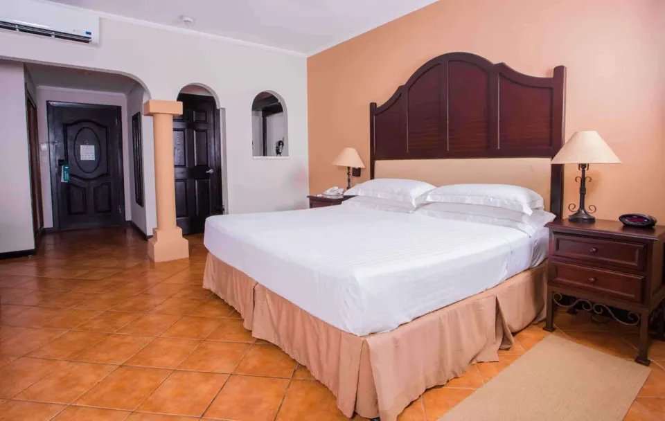 Deluxe Room king bed with arched entry and bedside tables at Occidental Papagayo.