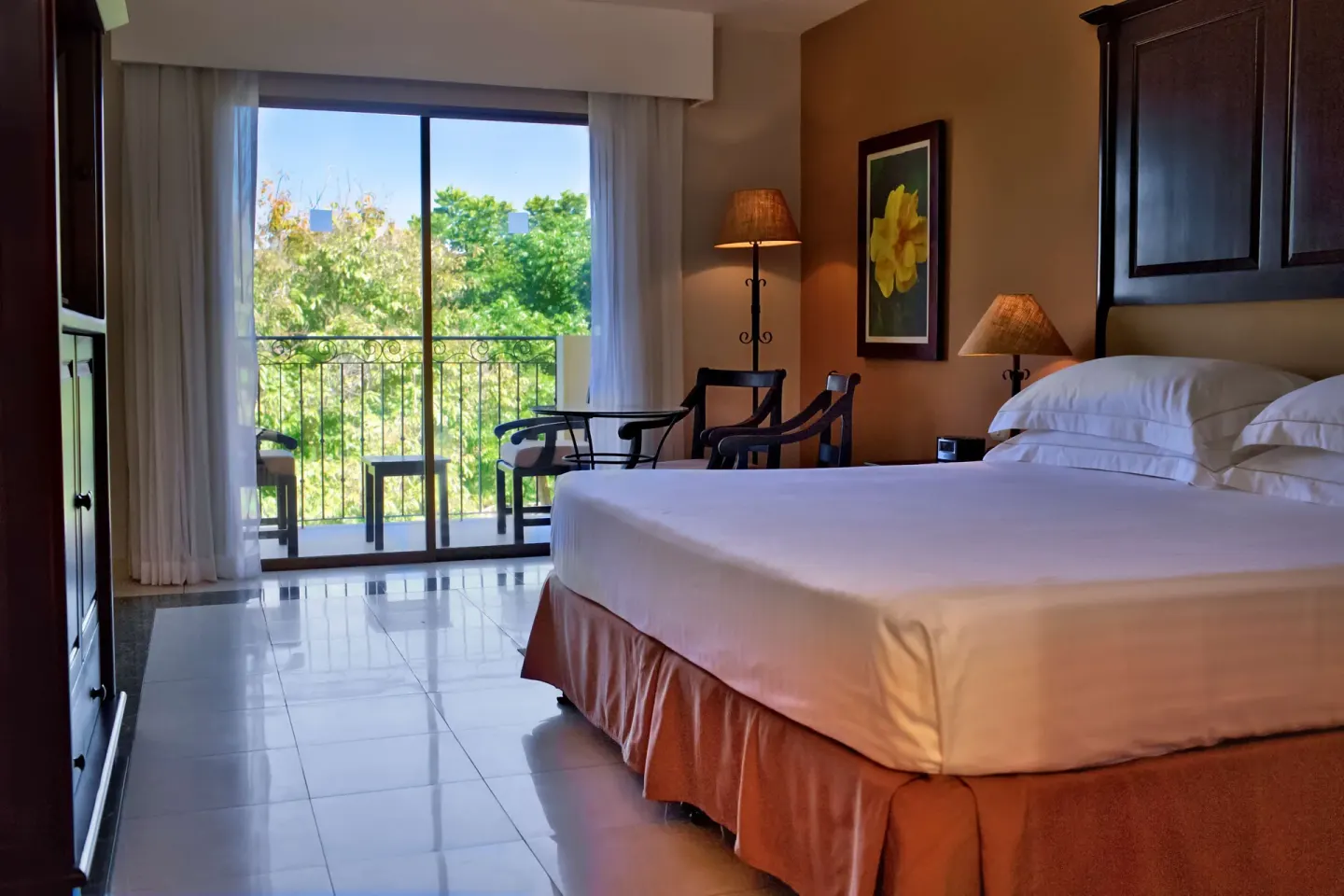 Deluxe Room king bed and balcony with greenery at Occidental Papagayo.