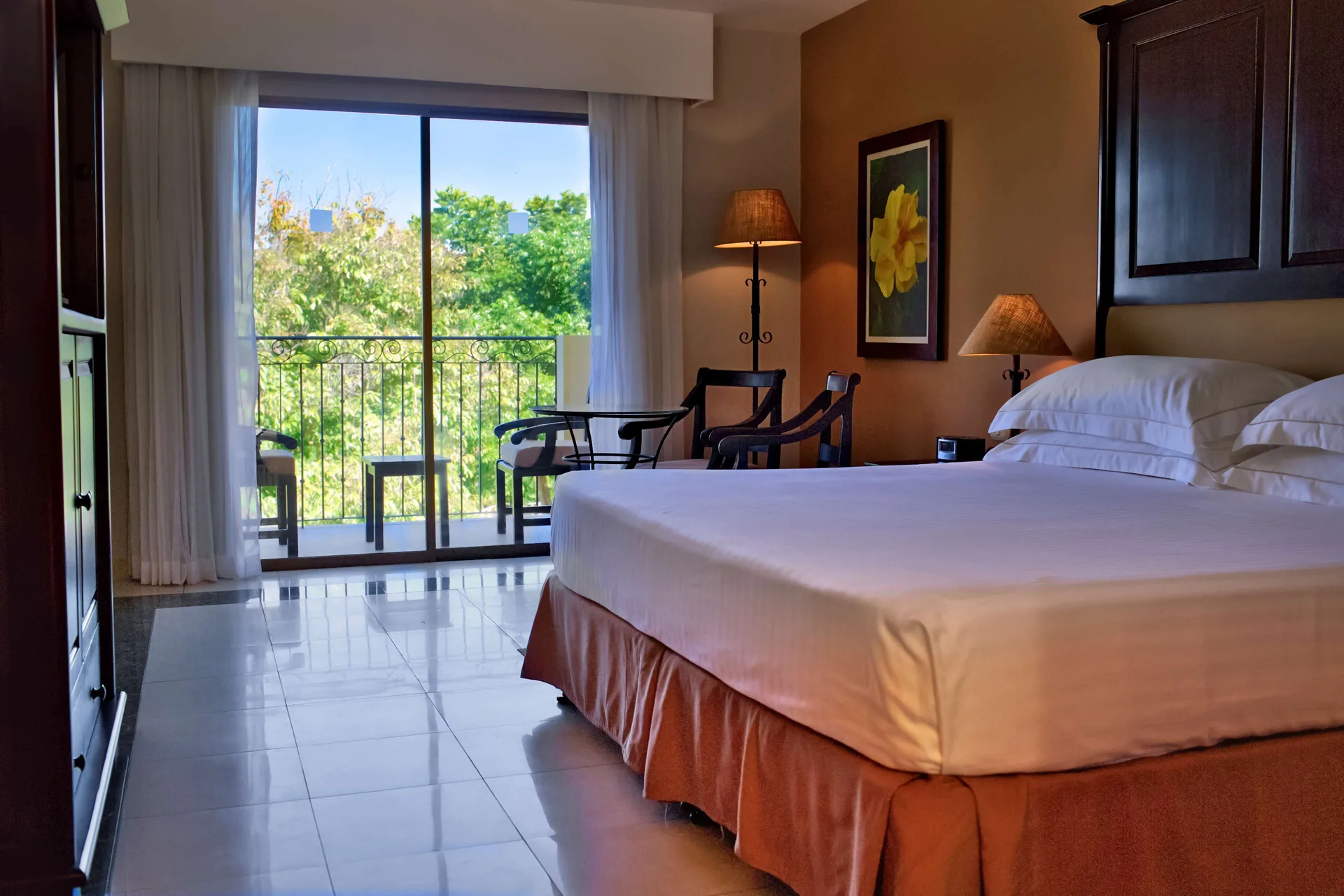 Deluxe Room king bed and balcony with greenery at Occidental Papagayo.