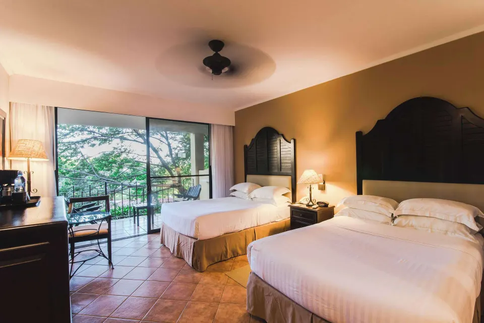 Deluxe Room with two beds and balcony seating at Occidental Papagayo.
