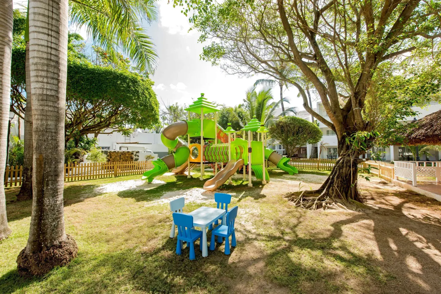 Children's play area with green slides and a blue table set at Occidental Punta Cana.