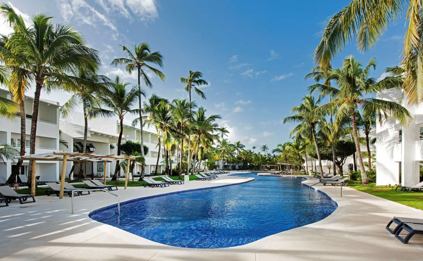 Long pool lined with palms, loungers, and white buildings at Occidental Punta Cana.