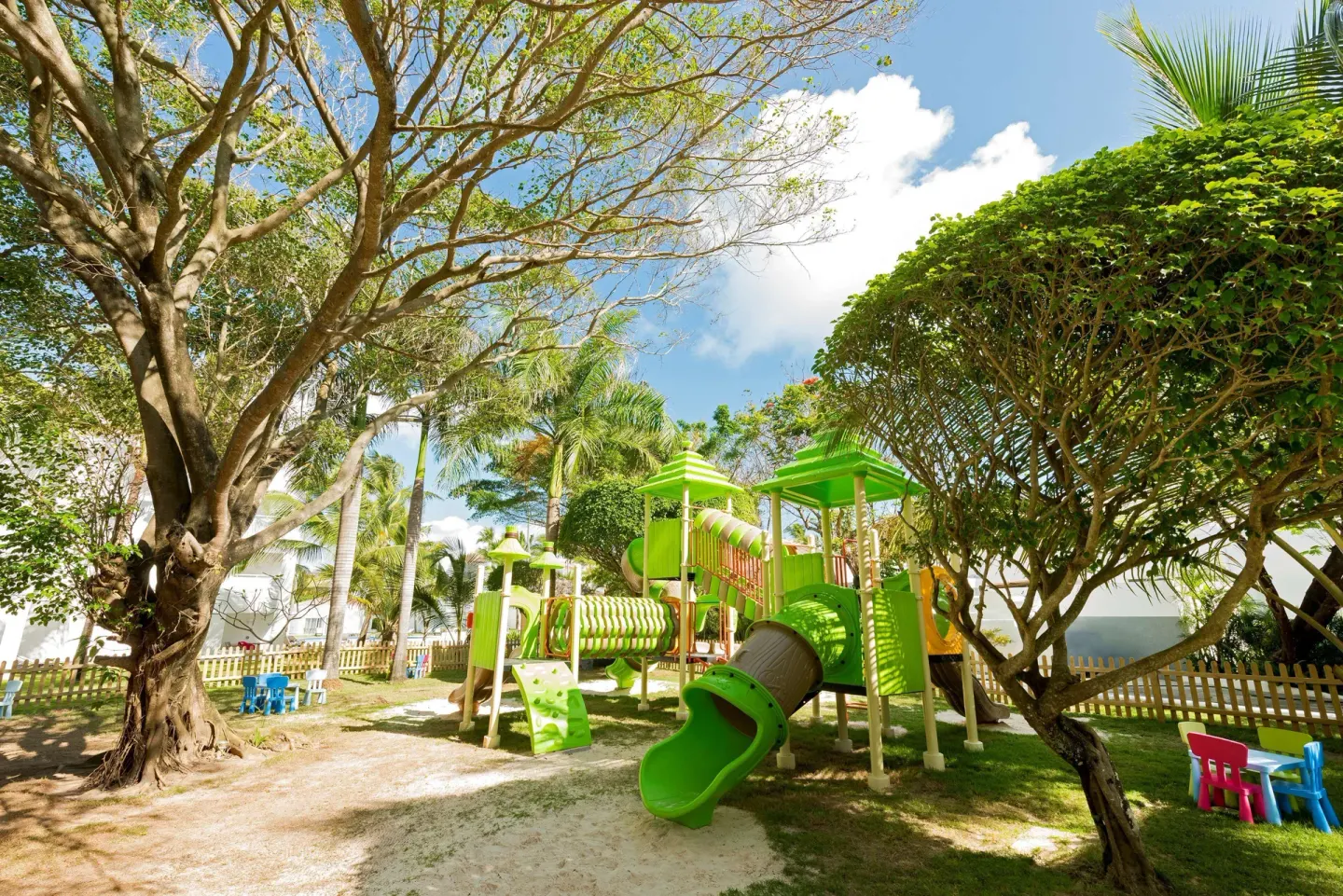 Outdoor children's playground with green slides and palm trees at Occidental Punta Cana.