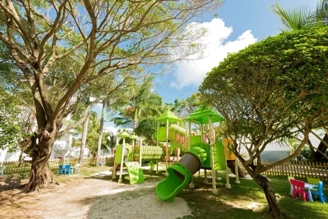 Outdoor children's playground with green slides and palm trees at Occidental Punta Cana.