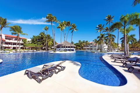 Large blue resort pool with islands of palms and sun loungers at Occidental Punta Cana.