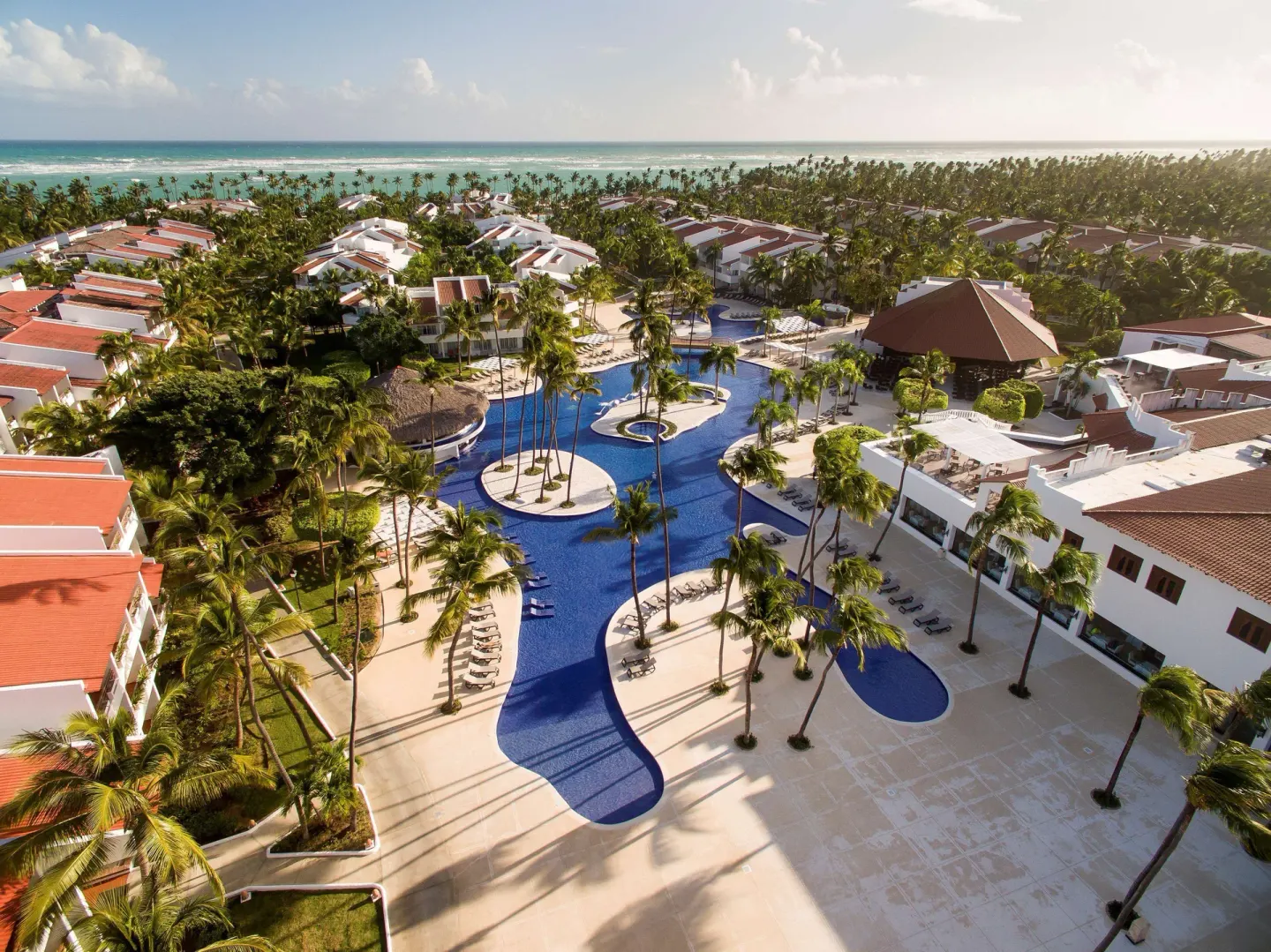 Wide aerial view of pools, palms, buildings, and ocean at Occidental Punta Cana.