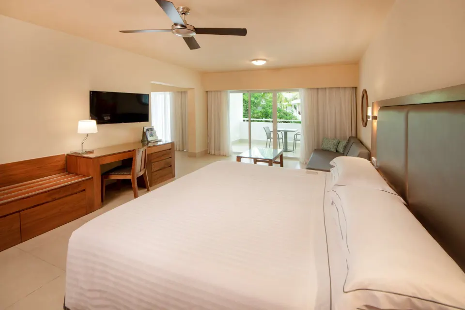 Family Junior Suite king bed, sitting area and balcony at Occidental Punta Cana.