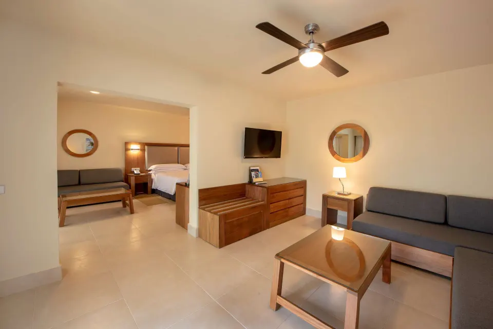 Family Junior Suite living area with sofa and bedroom beyond at Occidental Punta Cana.