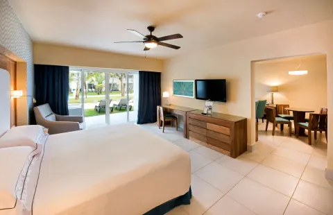 Suite bedroom with king bed, desk, TV, and patio doors at Occidental Punta Cana.