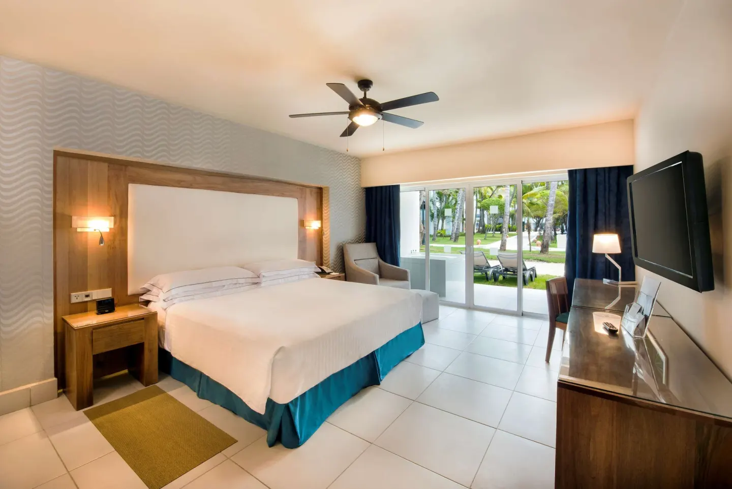 Suite king bedroom with wood headboard and patio view at Occidental Punta Cana.