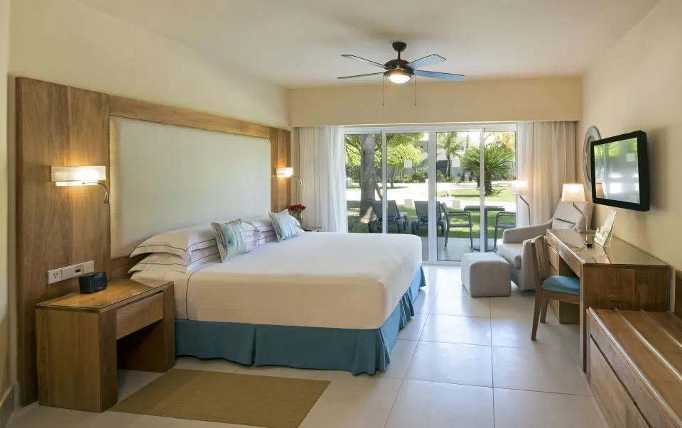 Superior Room with king bed, terrace doors, armchair and desk at Occidental Punta Cana.