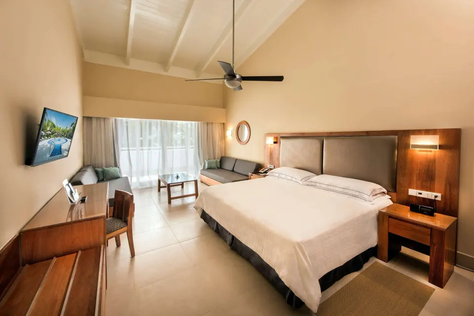 Superior Room Oceanfront with king bed, high ceiling, sofa and TV at Occidental Punta Cana.