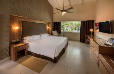 Royal Level Superior Room with king bed, desk, TV, and garden window at Occidental Punta Cana.