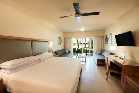 Superior Room king bed with sofas, desk, TV, and patio view at Occidental Punta Cana.