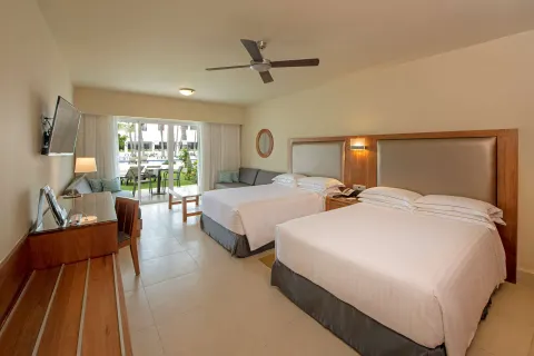 Superior Room with two beds, desk, TV, sofa, and patio at Occidental Punta Cana.