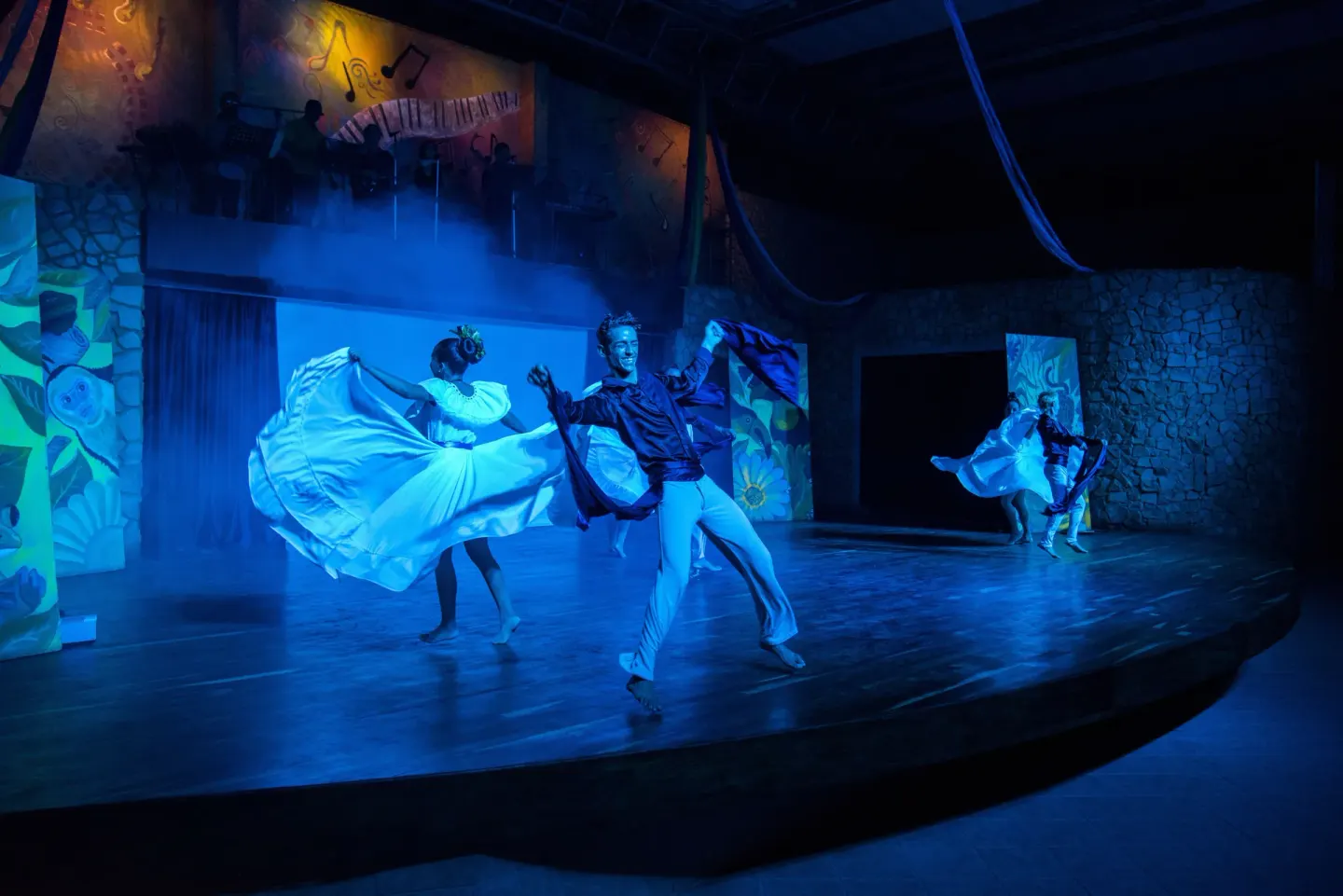 Dancers in flowing costumes perform in blue stage light at Occidental Tamarindo.