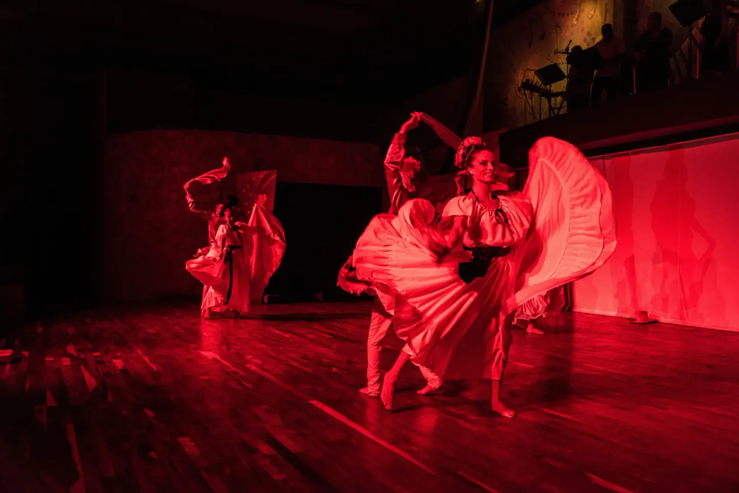 Dancers in white costumes perform on a red-lit stage at Occidental Tamarindo.