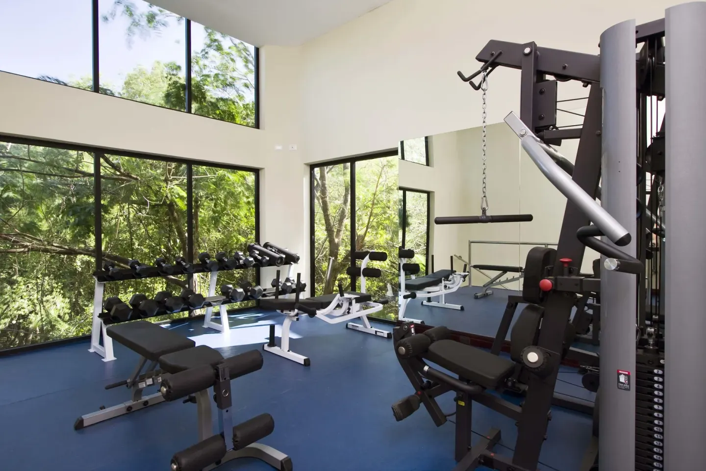 Fitness center with weight machines and forest-view windows at Occidental Tamarindo.