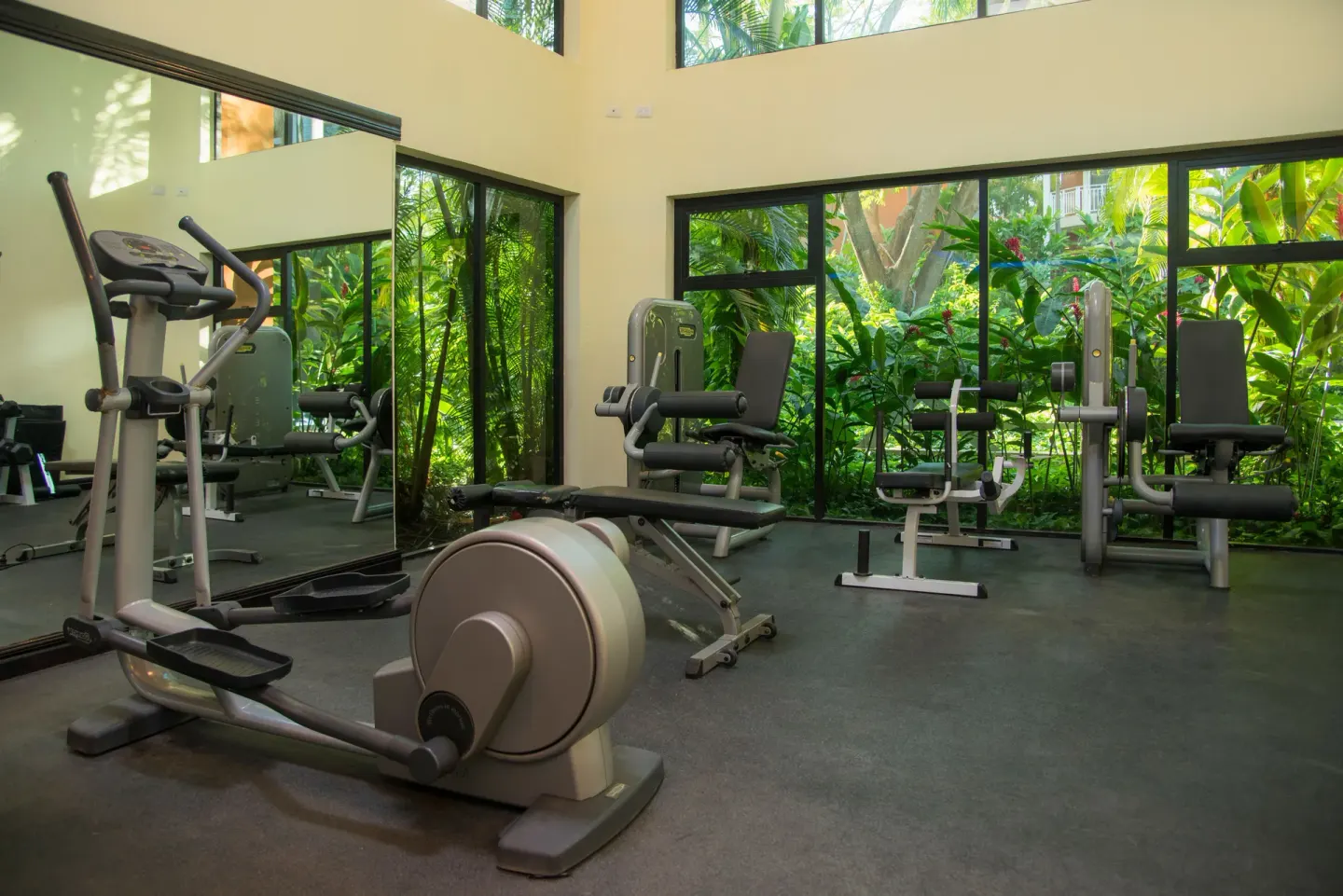 Fitness room with cardio and strength equipment beside garden windows at Occidental Tamarindo.