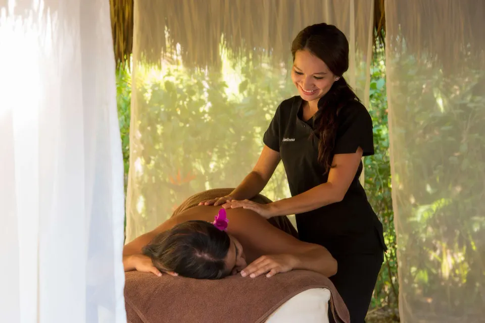 Spa therapist giving a massage in a curtained garden cabana at Occidental Tamarindo.