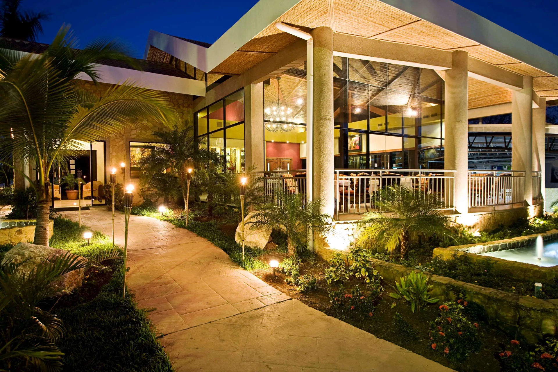 Illuminated resort building and garden walkway at night at Occidental Tamarindo.