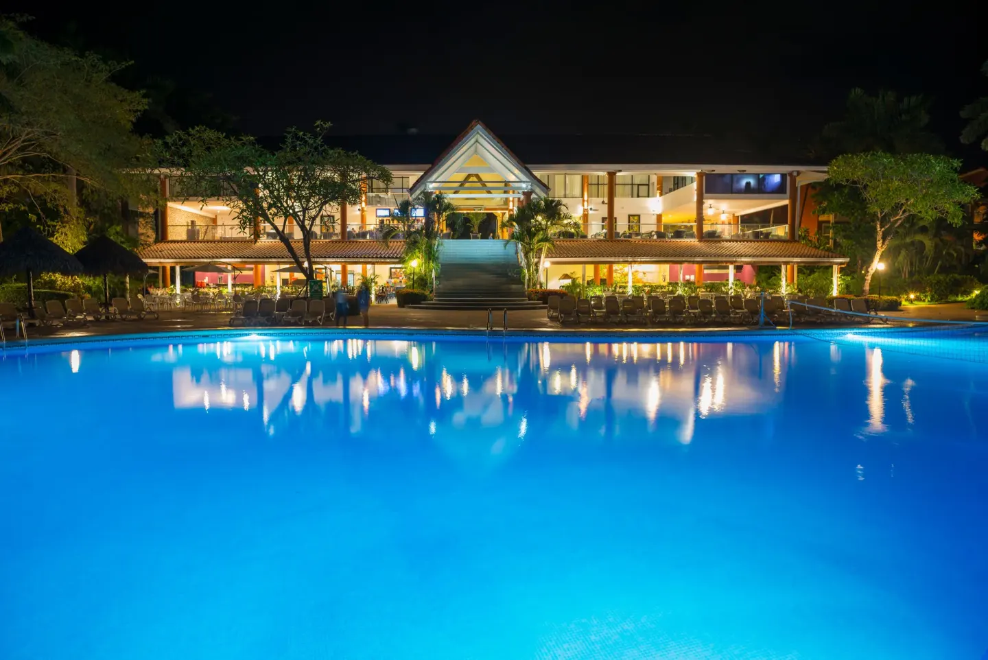 Illuminated pool and resort building reflected at night at Occidental Tamarindo.