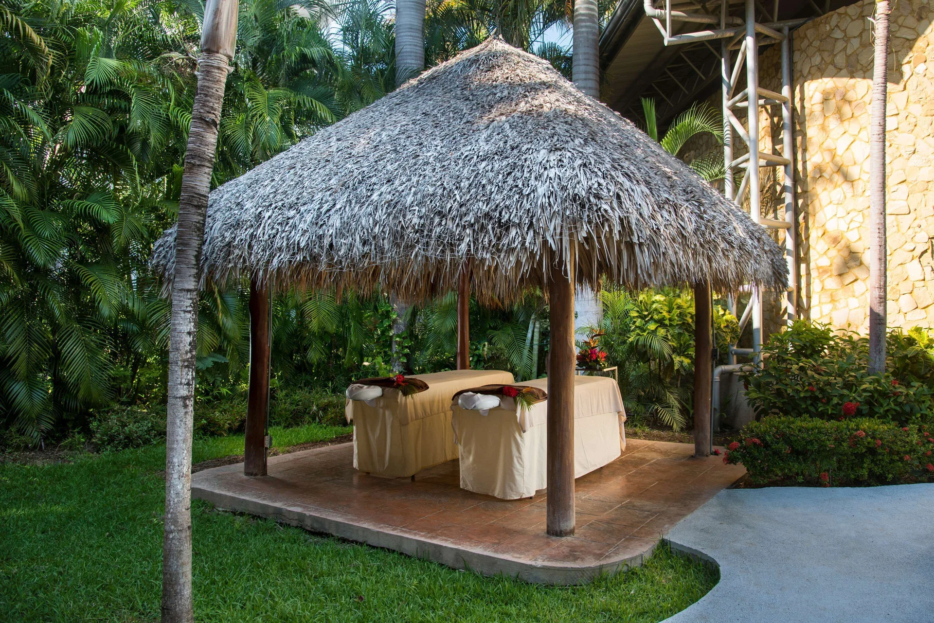 Outdoor massage palapa with two treatment tables in gardens at Occidental Tamarindo.