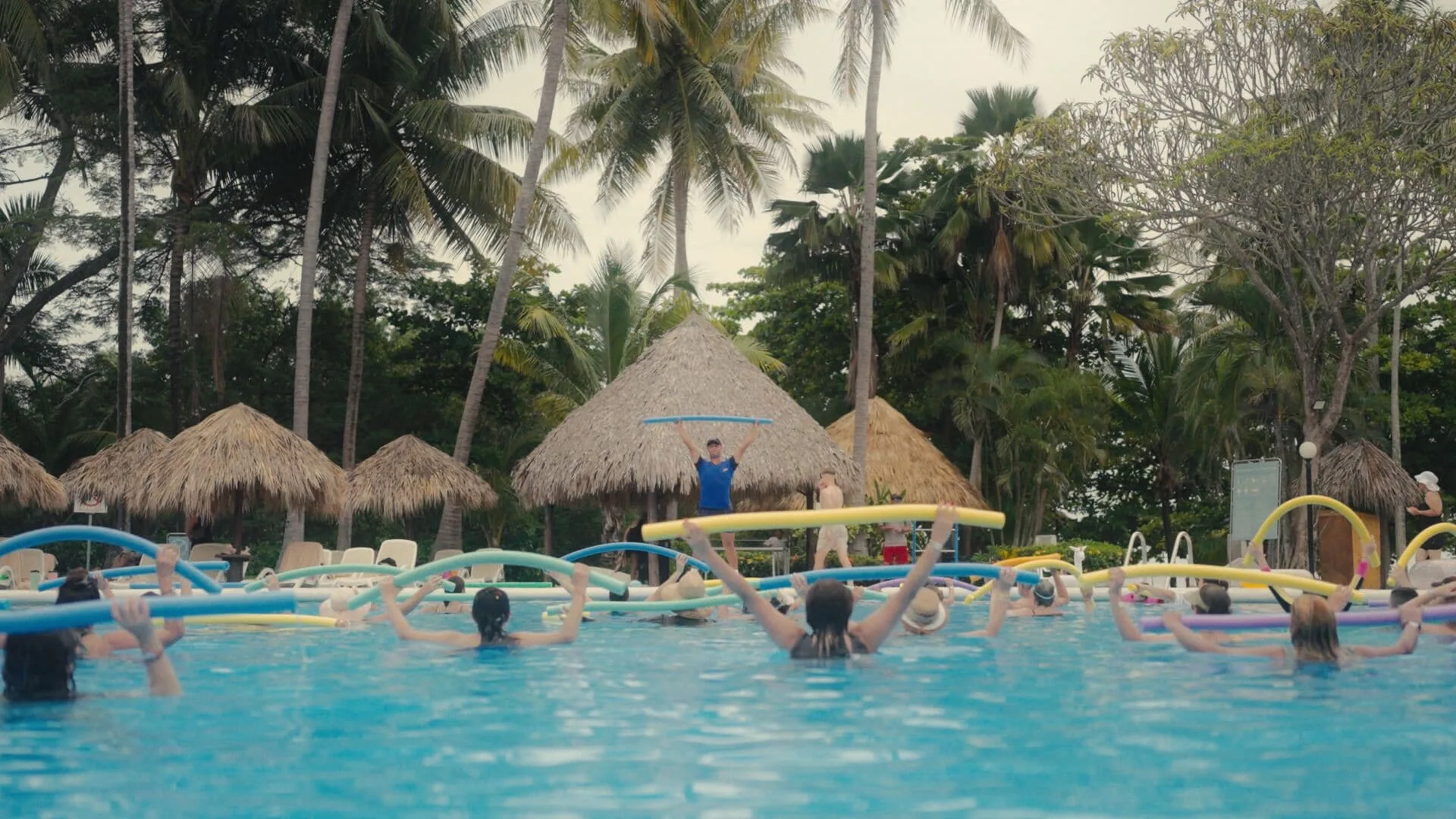 Guests join a pool fitness activity with foam noodles at Occidental Tamarindo.