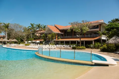 Shallow pool area with glass railing and resort building at Occidental Tamarindo.