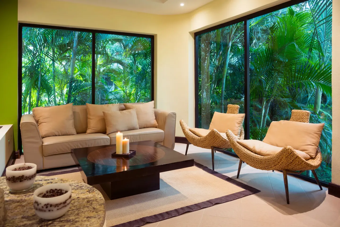 Spa lounge with sofa, woven chairs, and tropical window views at Occidental Tamarindo.