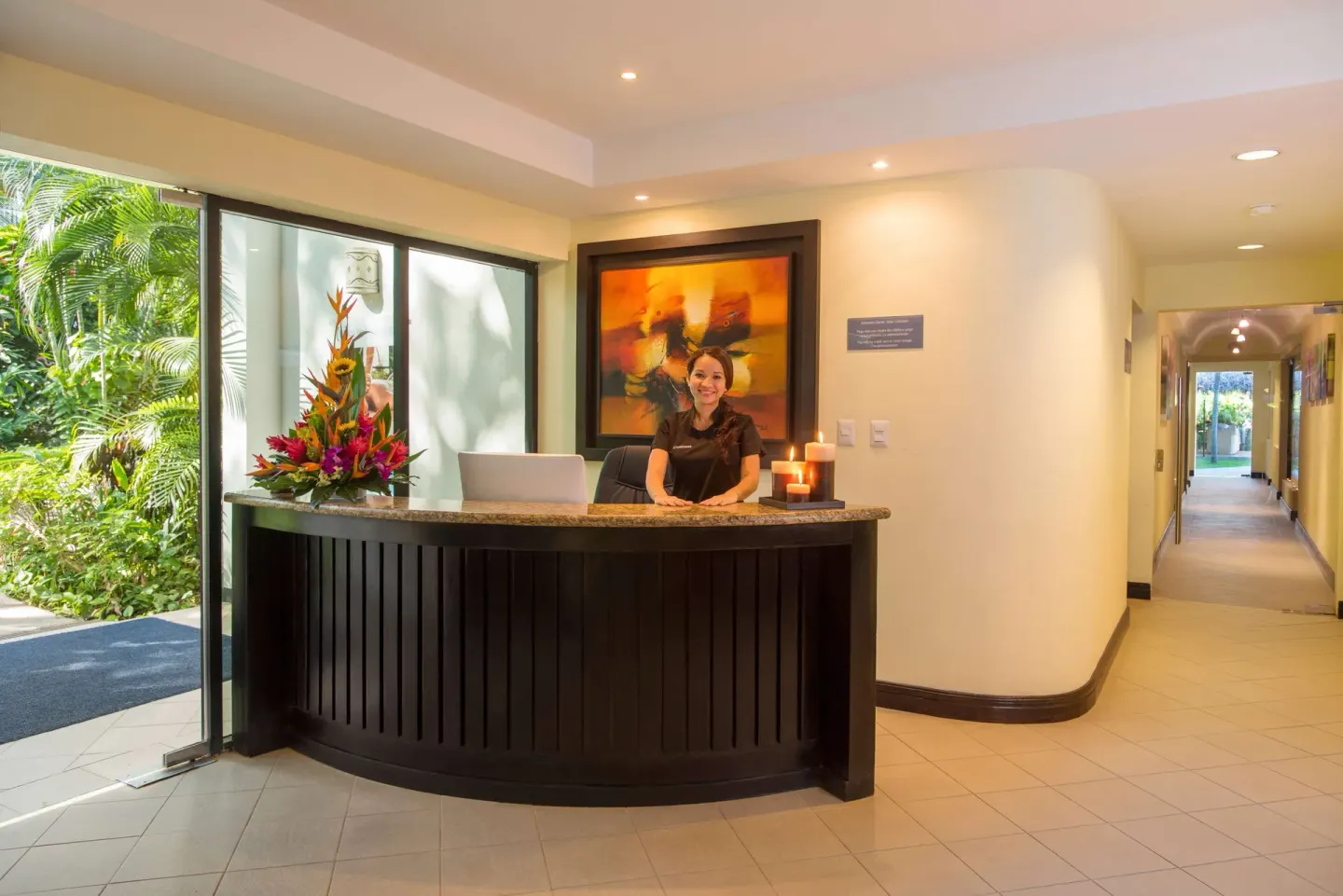 Spa reception desk with floral arrangement and hallway at Occidental Tamarindo.