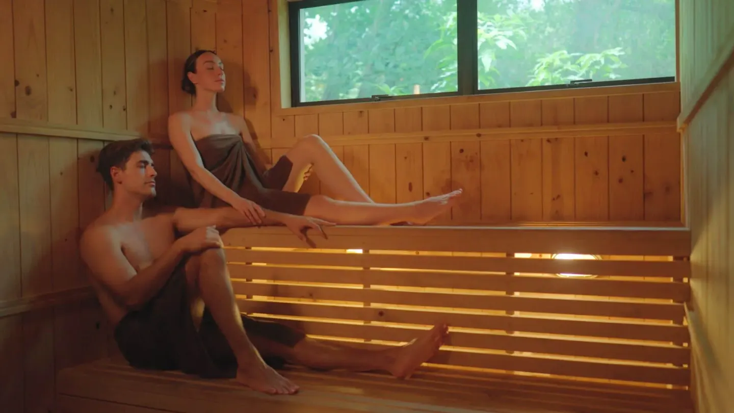 Wood-paneled sauna with two guests relaxing on benches at Occidental Tamarindo.