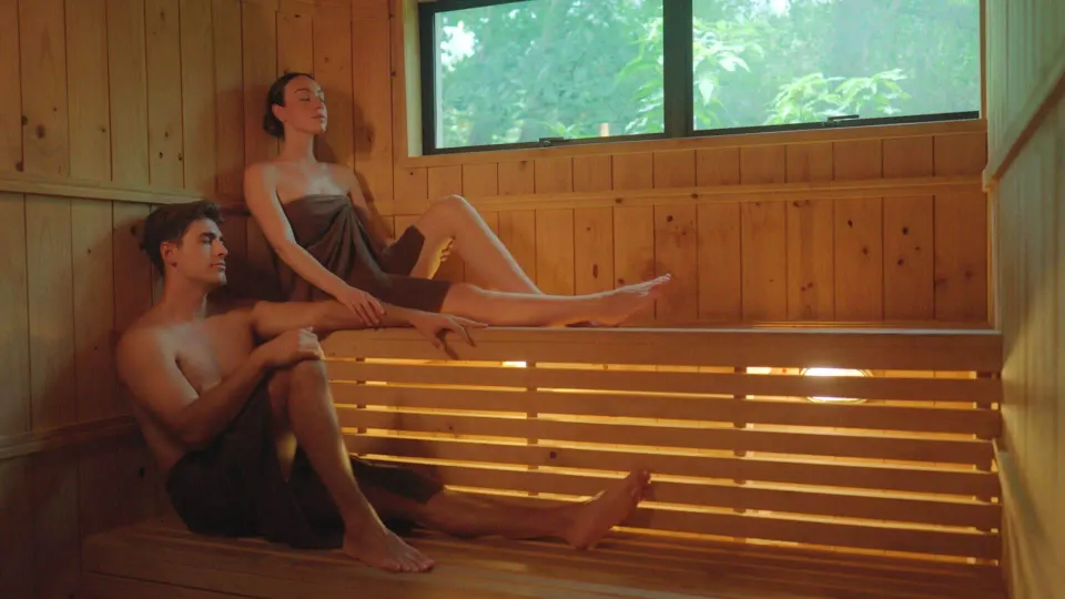 Wood-paneled sauna with two guests relaxing on benches at Occidental Tamarindo.