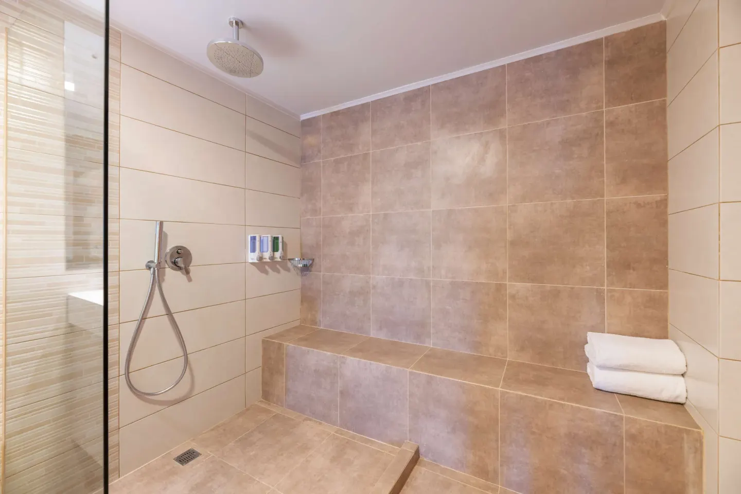 Duplex suite walk-in shower with bench and towels at Occidental Tamarindo.