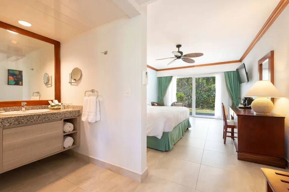 Superior Room bathroom vanity and bedroom with king bed at Occidental Tamarindo.