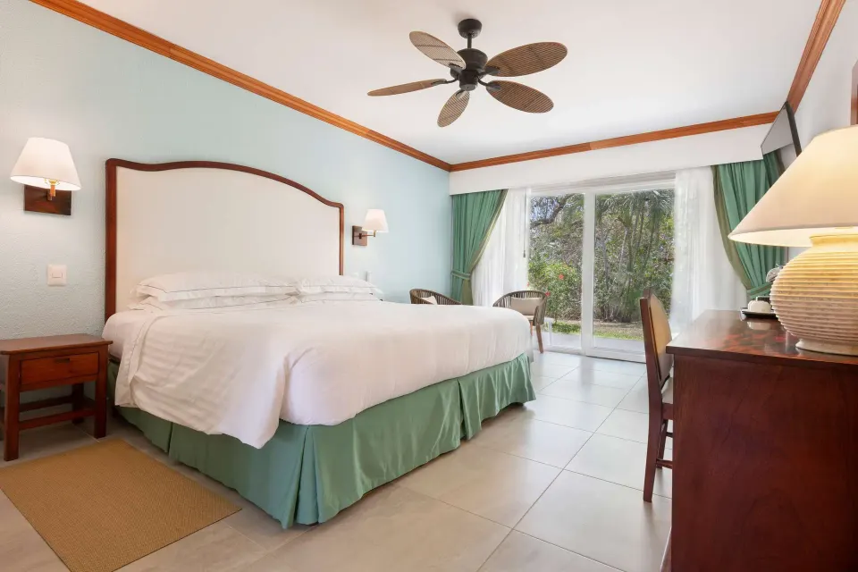 Superior Room king bed with dresser and garden-facing doors at Occidental Tamarindo.