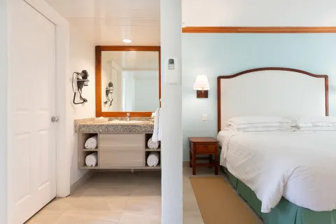 Superior Room king bed beside an open vanity area at Occidental Tamarindo.