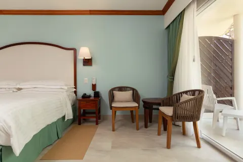 Superior Room king bed with chairs and patio doors at Occidental Tamarindo.