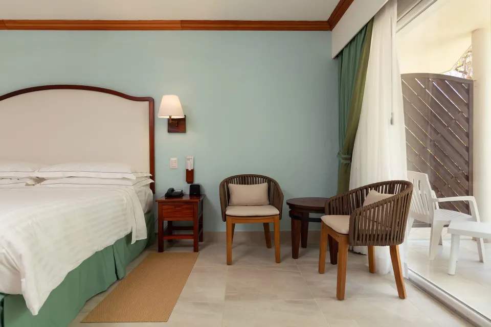 Superior Room king bed with chairs and patio doors at Occidental Tamarindo.