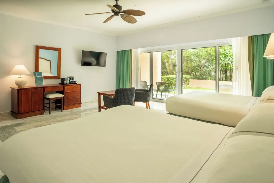 Superior Room with two beds, desk, and patio doors at Occidental Tamarindo.