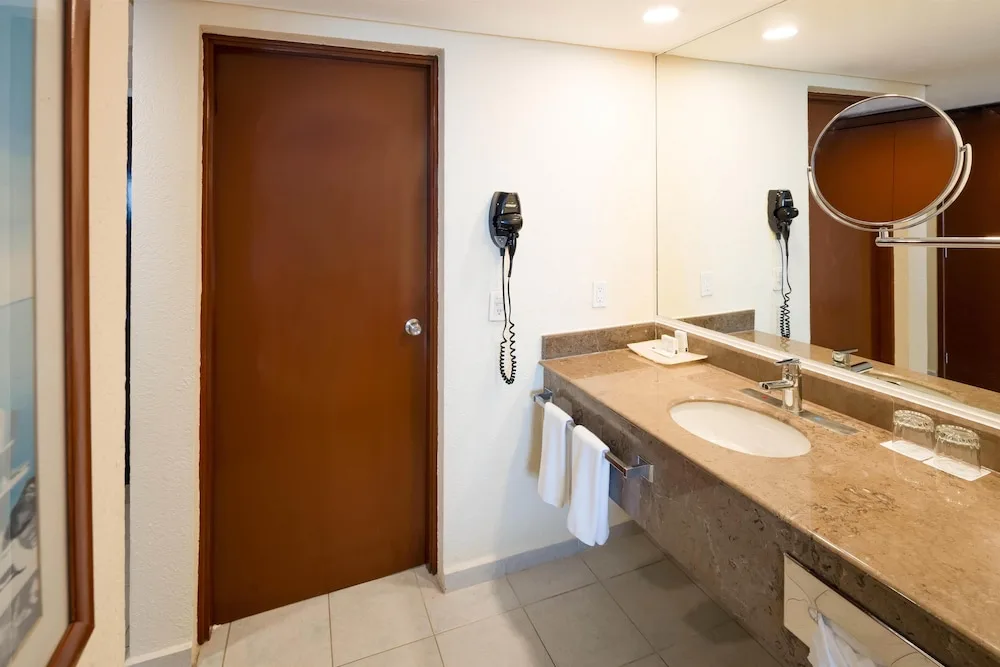 Guest bathroom vanity with sink, mirror, towels, and amenities at Occidental Tucancún.