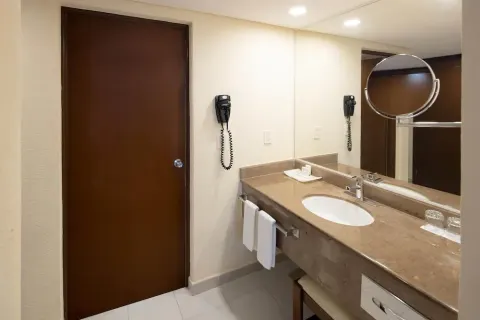 Bathroom vanity with sink, mirror, hair dryer, and towels at Occidental Tucancún.