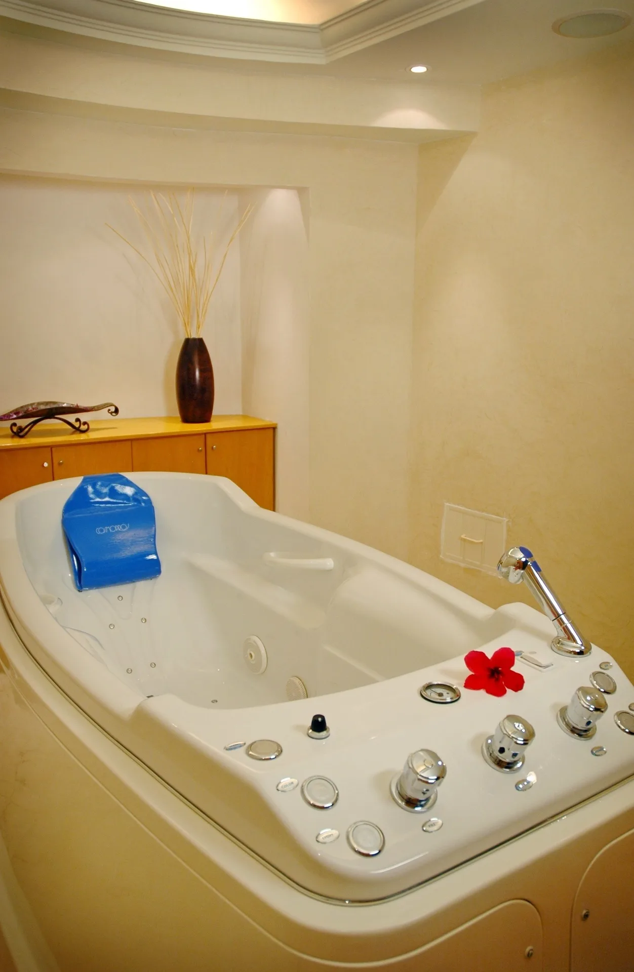 Indoor spa tub with controls and a red flower at Occidental Tucancún.