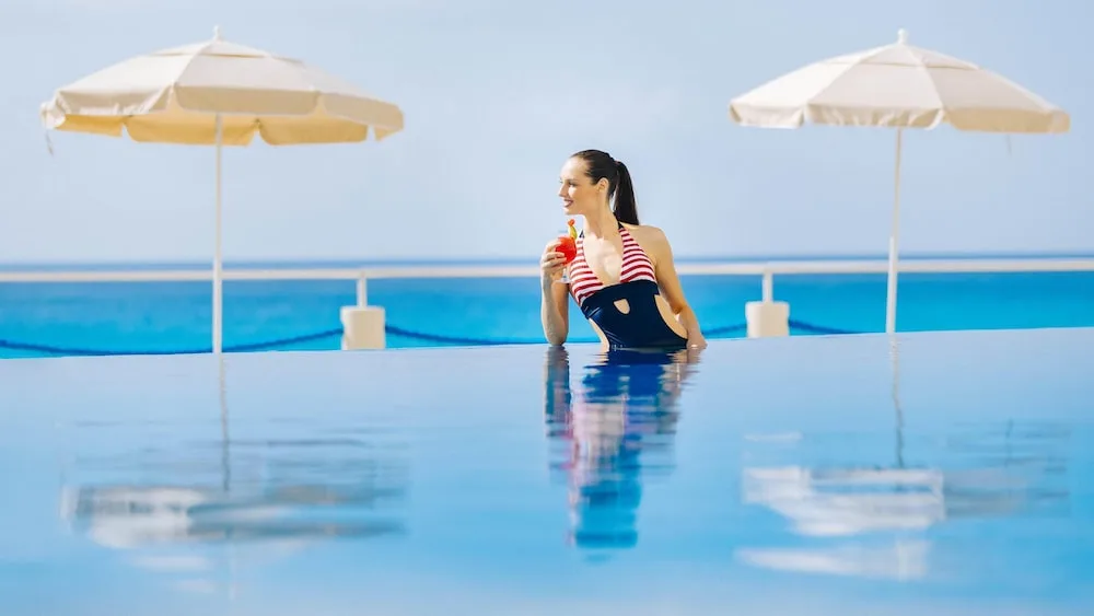Woman holding a drink in an infinity-style pool at Occidental Tucancún.