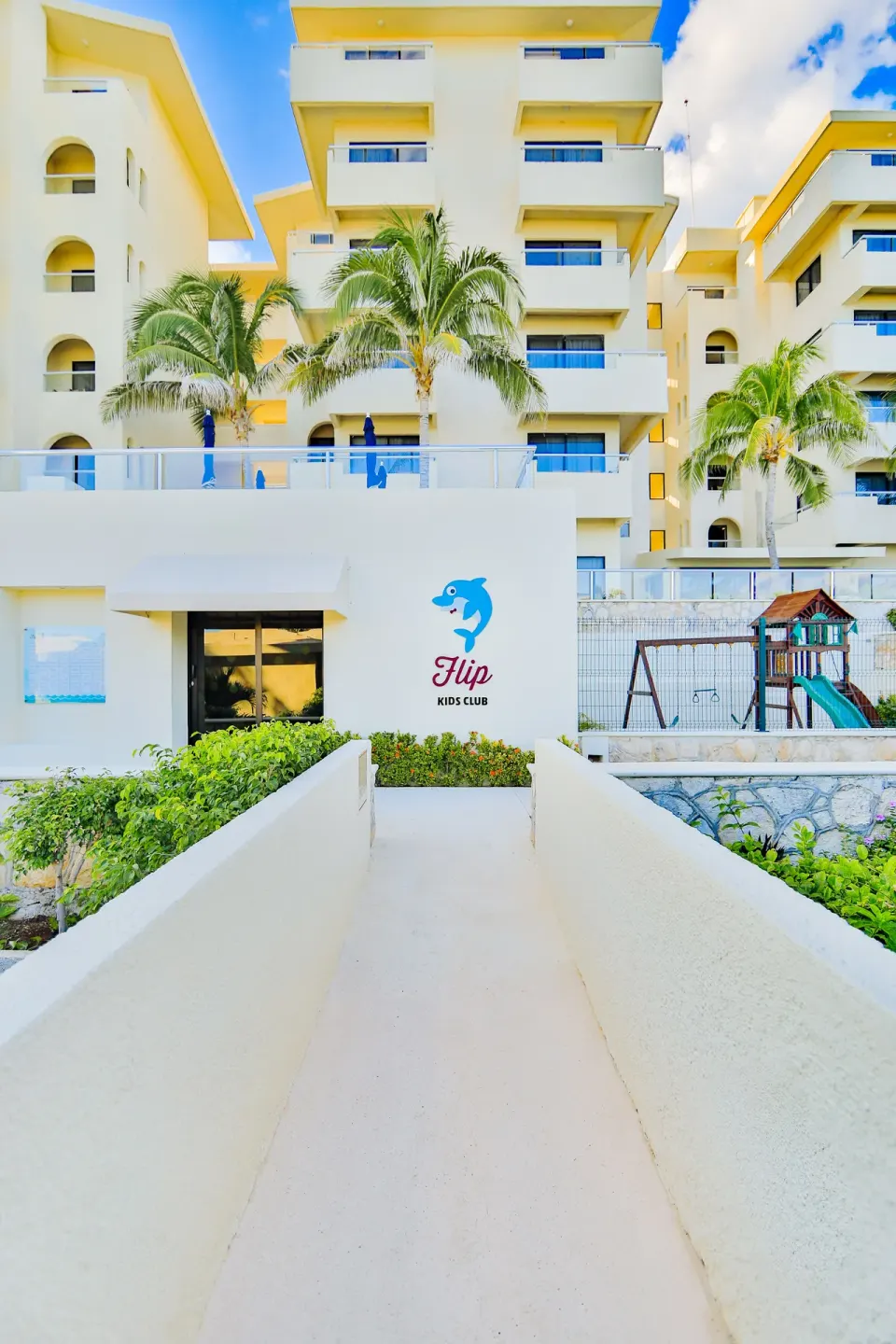 Walkway to the kids club with resort buildings behind it at Occidental Tucancún.
