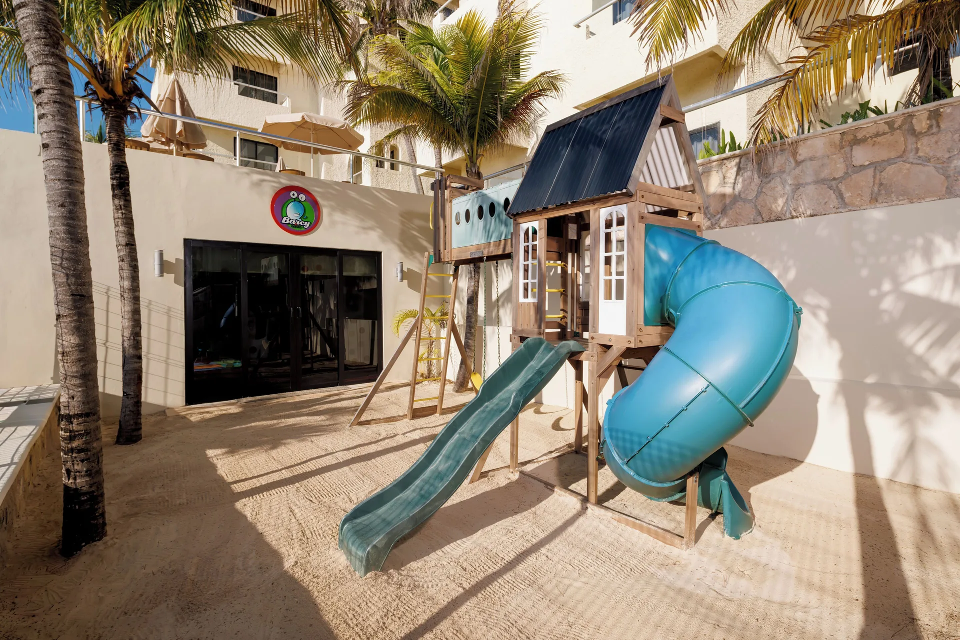 Children's play structure with slides in a courtyard at Occidental Tucancún.
