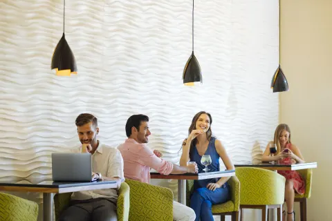 Guests seated at small lounge tables with pendant lights at Occidental Tucancún.