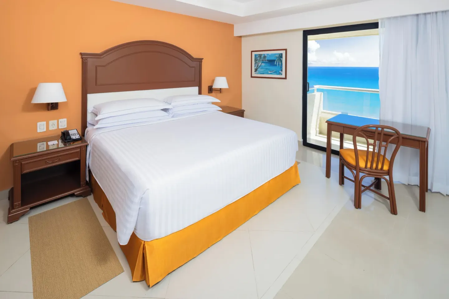 King-bed ocean-view guest room with balcony seating at Occidental Tucancún.