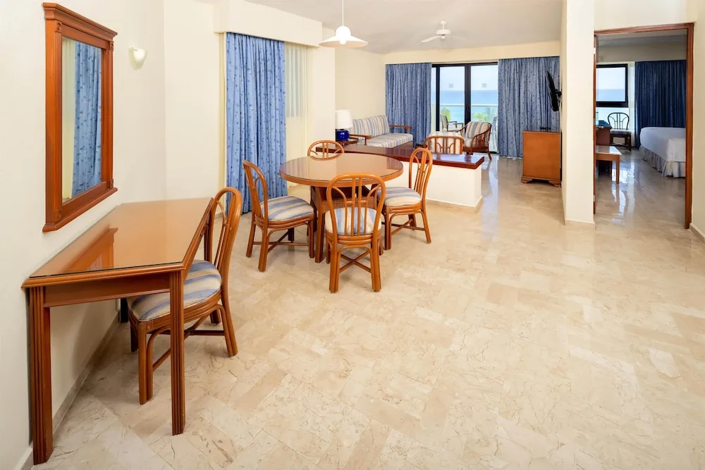 Suite living and dining area with ocean-facing windows at Occidental Tucancún.